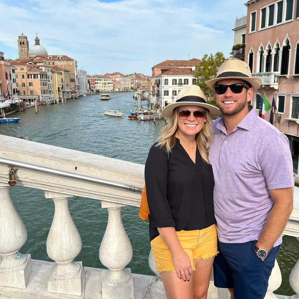 Britt and Ian Strum posing for a picture in front of a river in Italy.