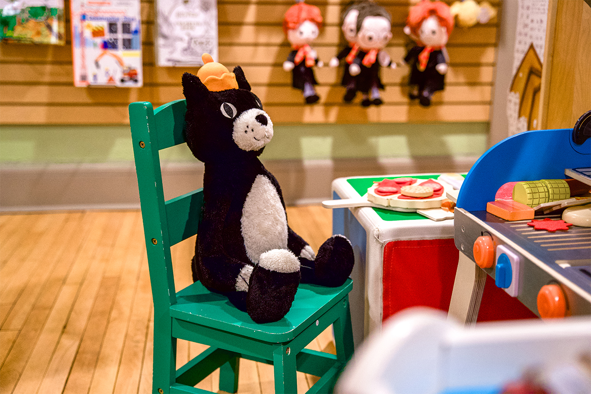 A Jellycat stuffed animal sitting on a child's play chair in a toy store.