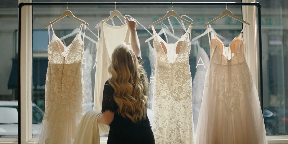 Erin Rallis hangs wedding dresses in the window of Sioux Falls bridal shop Marie and Marie Bridal.