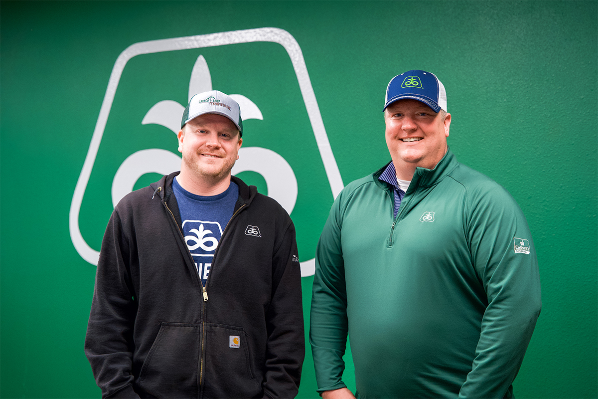 Rob Thuringer and Dave Ellens standing in front of a Pioneer-logoed green wall.