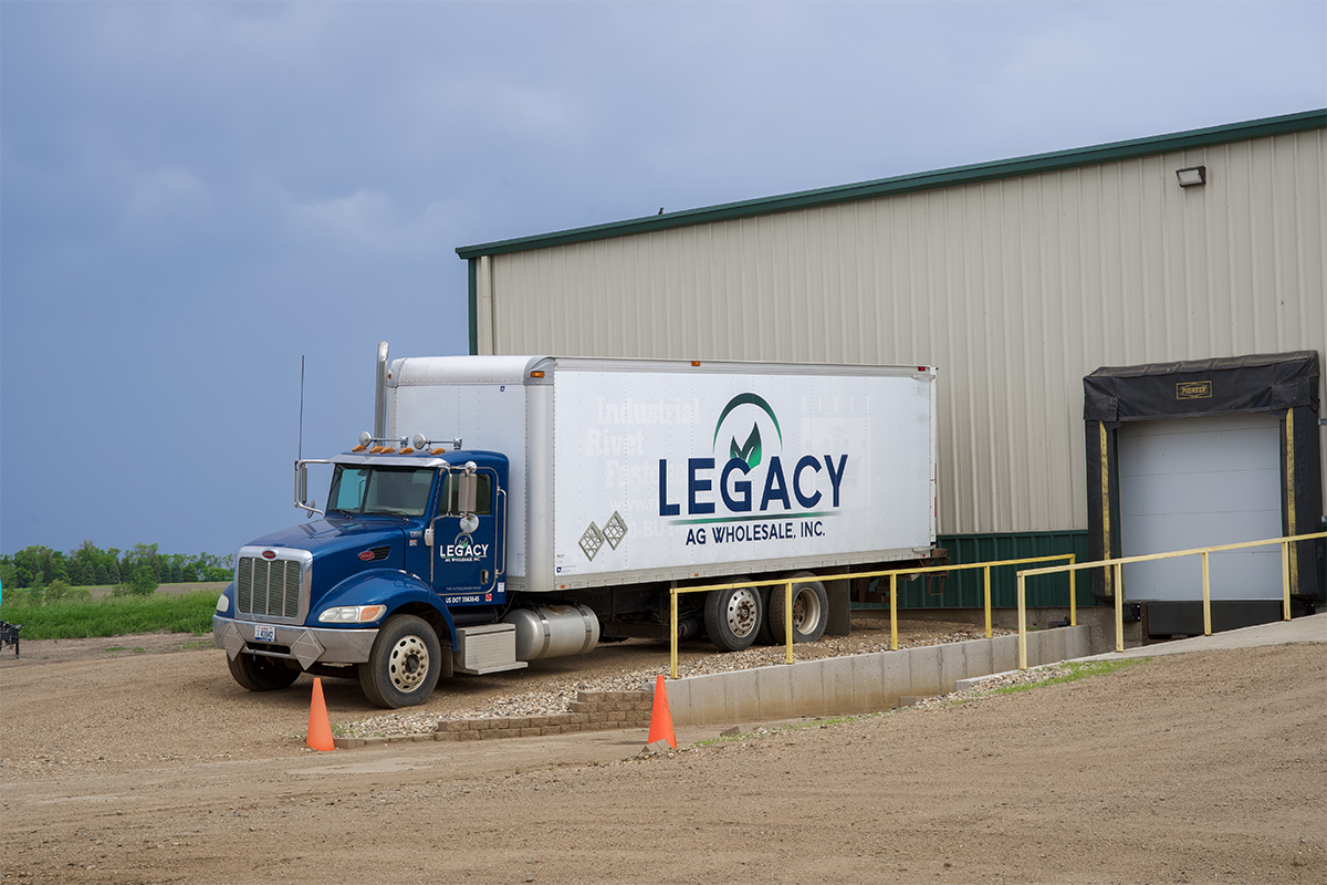 A delivery truck with the Legacy Ag Wholesale logo on its trailer.