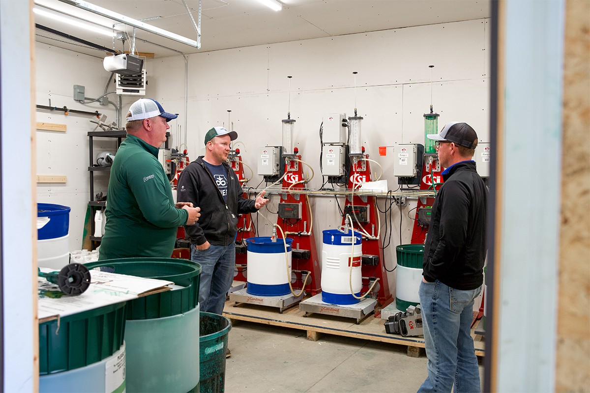 Dave Ellens and Rob Thuringer discussing crop products with a customer in their warehouse.