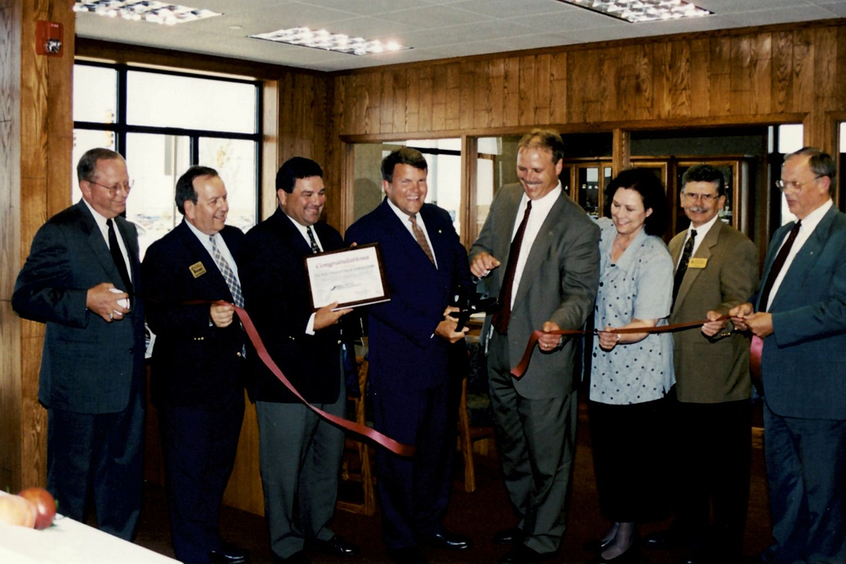 A group of people cutting a ribbon inside First National Bank's Benson Road branch.