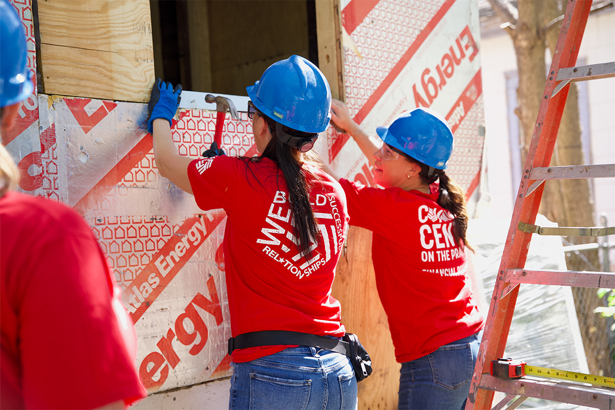 Two women hammering siding at Habitat for Humanity.