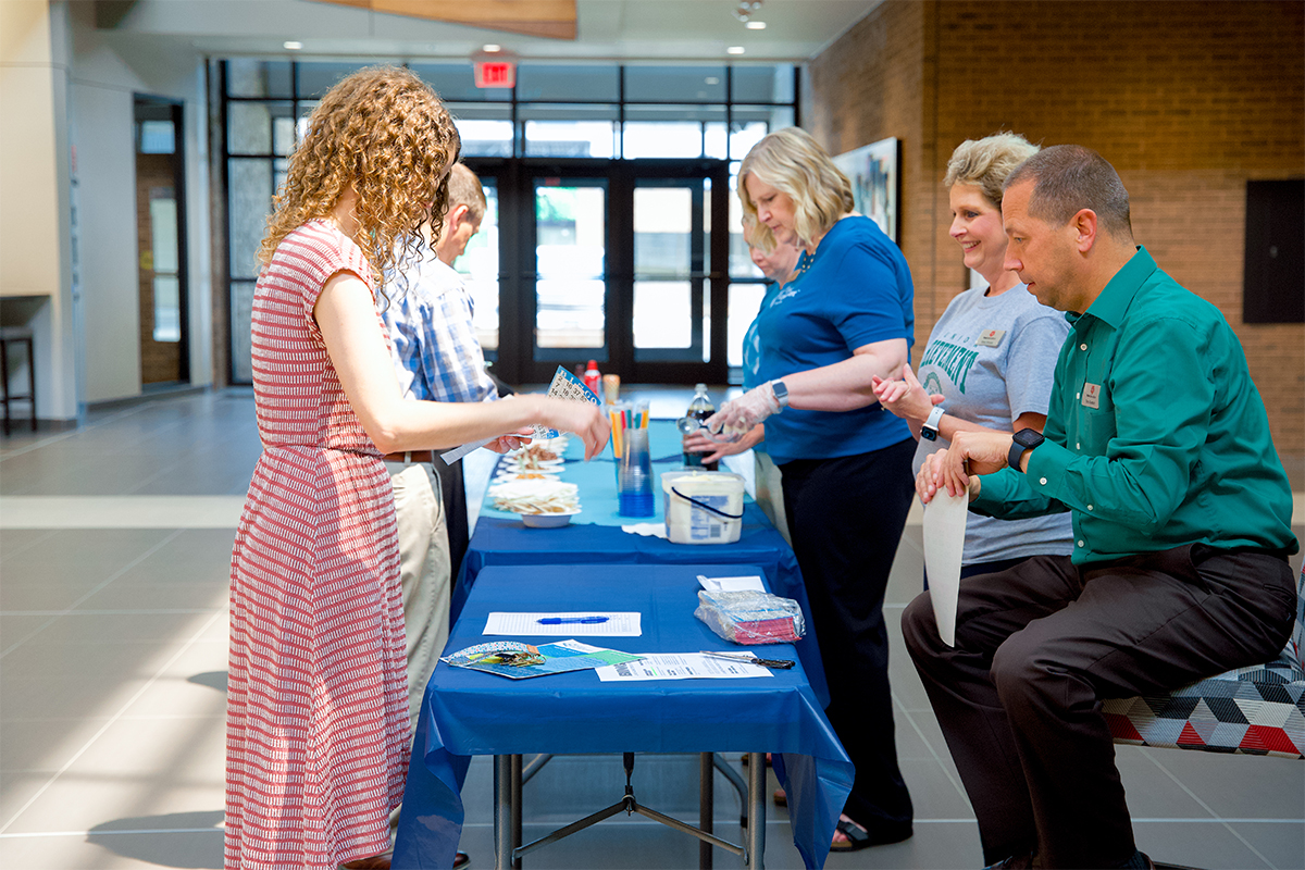 A young woman buying a bingo card at a Junior Achievement ice cream social.