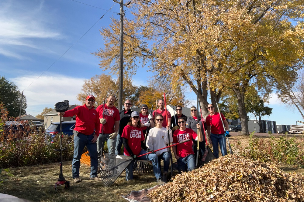 A group of First National Bank teammates raking leaves for Rake the Town.