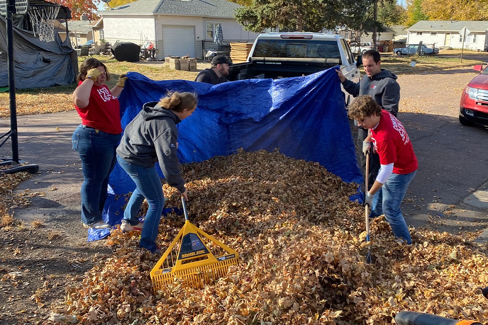 A group of First National Bank teammates raking leaves for Rake the Town.