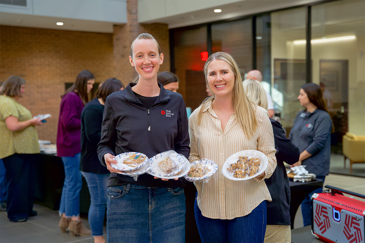 Two young women holding plates of goodies from a bake sale.