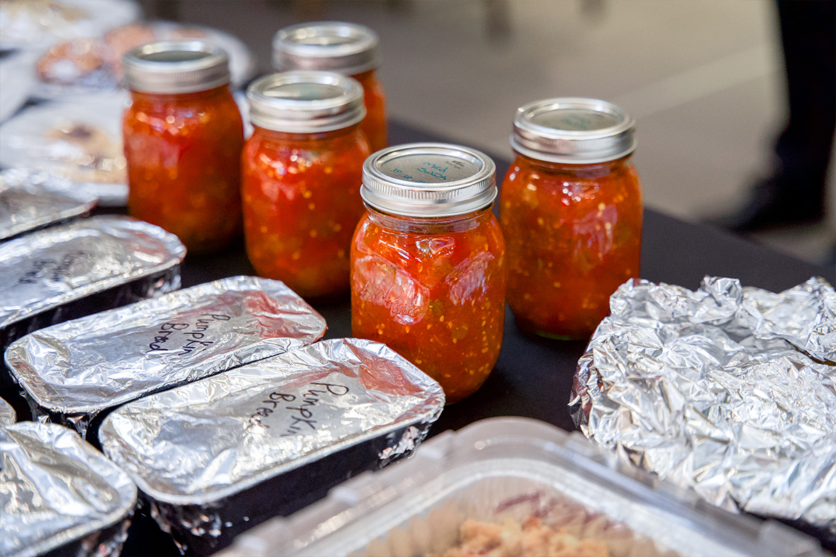 Jars of homemade salsa and pumpkin loaves sitting on a table.