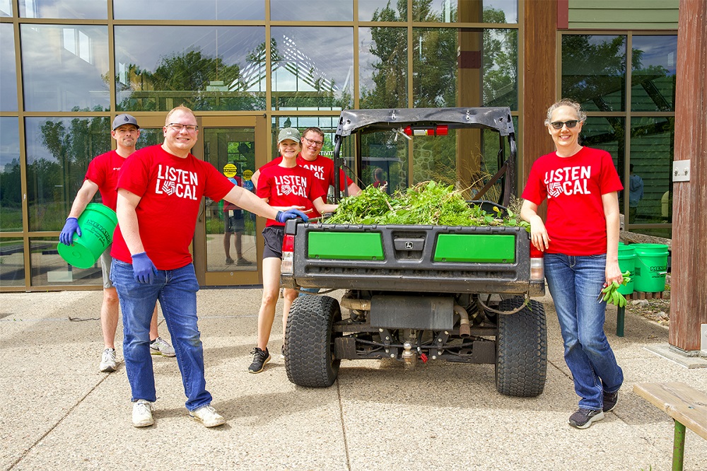 First National Bank teammates standing next to a side-by-side full of weeds at The Outdoor Campus.