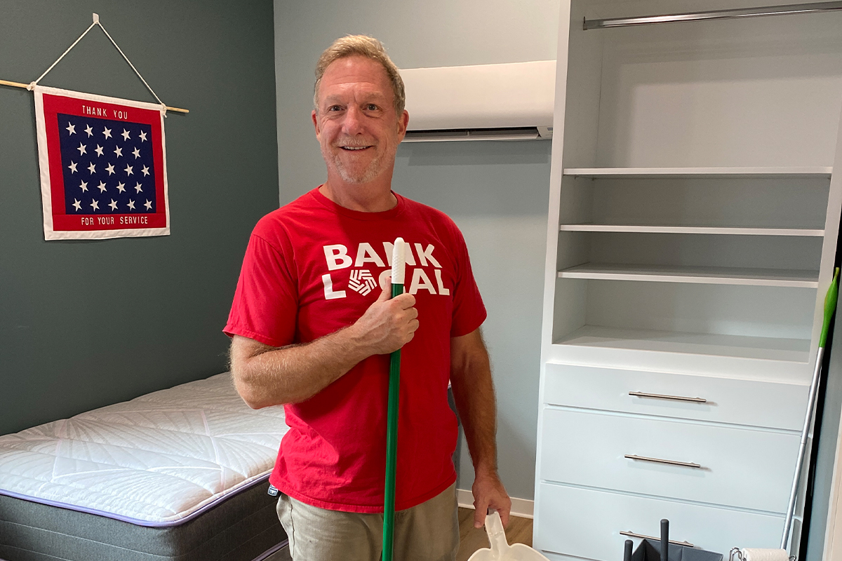 A man holding a broom in a tiny house at the Veterans Community Project.