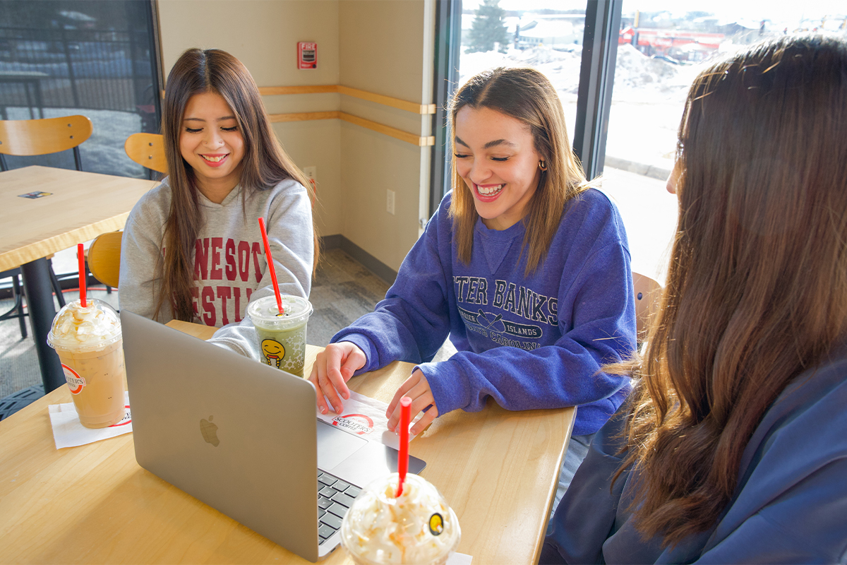 Three high school girls laughing while filling out a scholarship application at Scooter's.